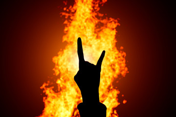 Silhouette of Rock and Roll hand sign against the fire background.