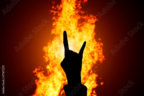Silhouette of Rock and Roll hand sign against the fire background.