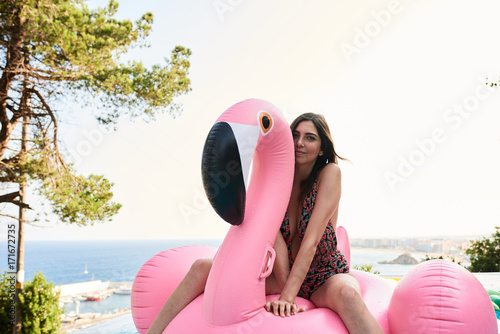 Smiling brunette on flamingo air mattress in pool