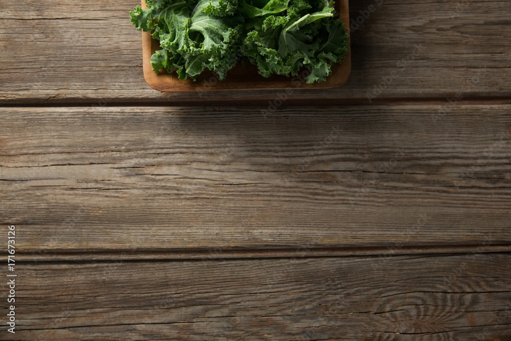 Fresh kale in bowl on wooden table