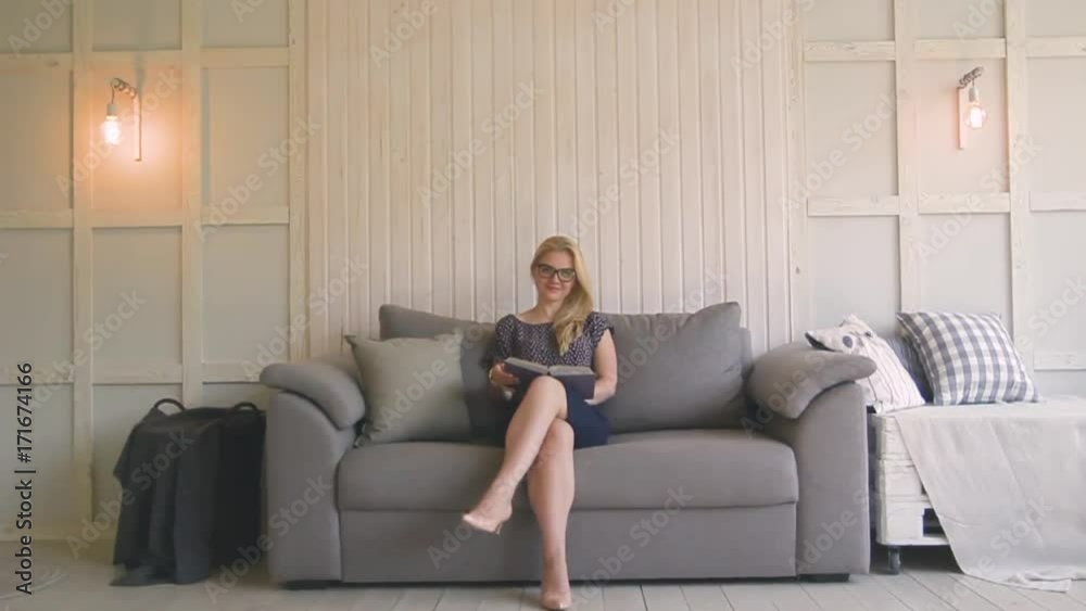 beautiful blond woman with glasses sits on the couch and throws up paper beautiful blond woman with glasses sits on the couch and throws up paper
