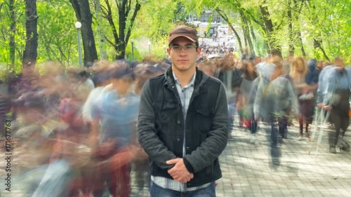 Man standing alone in blurred crowd, on background green trees. Time Lapse, Full HD photo