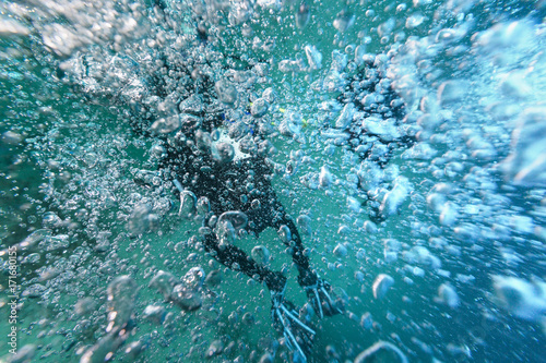 Scuba Divers underneath vast of air bubbles photo