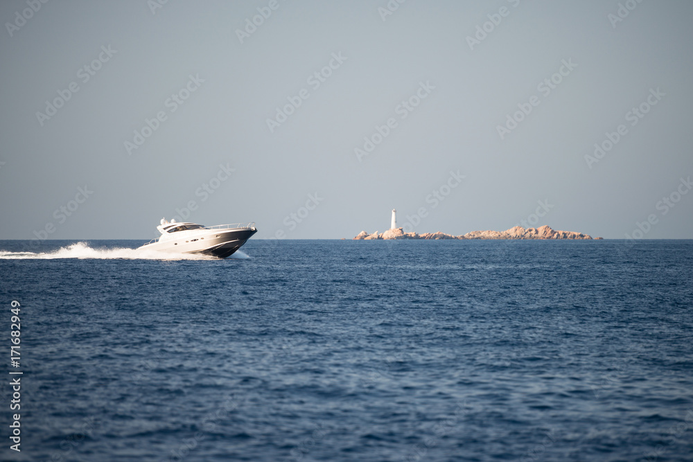 Small motor boat on sea, small island in background Small motor boat on sea, small island in background