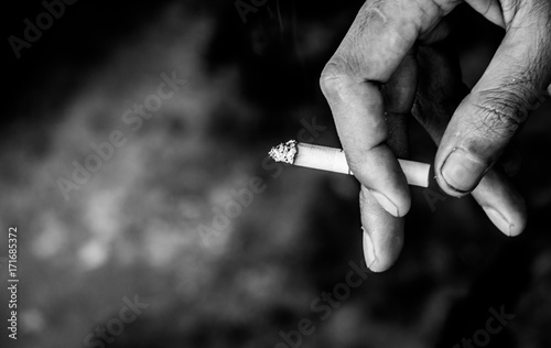 The image of a cigarette in the hands of a man smoking while standing