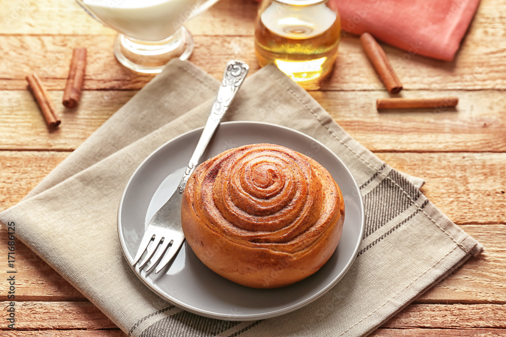 Sweet cinnamon roll and fork on plate Sweet cinnamon roll and fork on plate