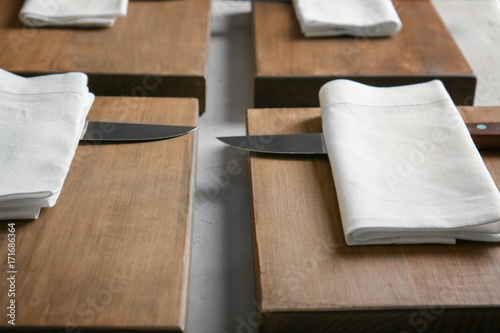 Knives with napkins and wooden boards on kitchen table. Cooking classes concept