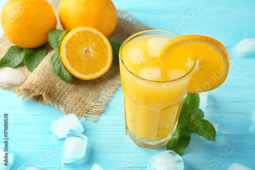 Composition with glass of fresh juice and oranges on wooden table