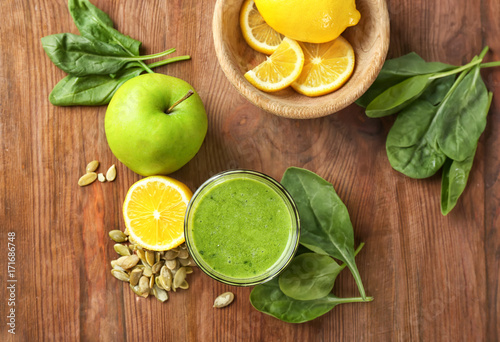 Glass of spinach smoothie on wooden background