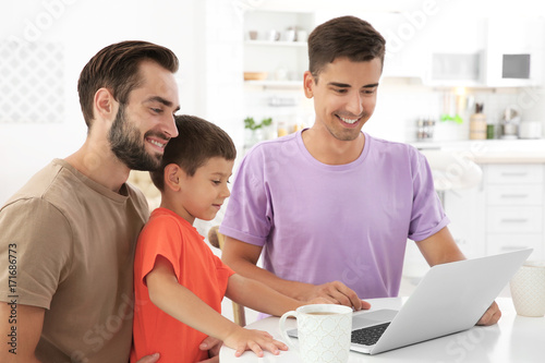 Happy male gay couple with foster son at home. Adoption concept
