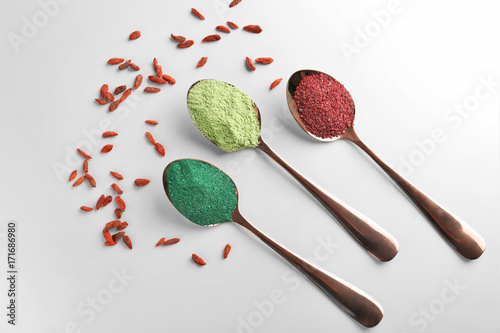 Various colorful superfood powders in spoons on light background