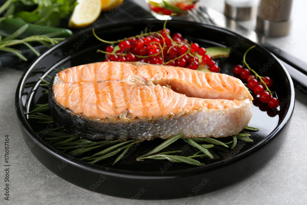 Grilled salmon steak with rosemary and red currant on plate Grilled salmon steak with rosemary and red currant on plate