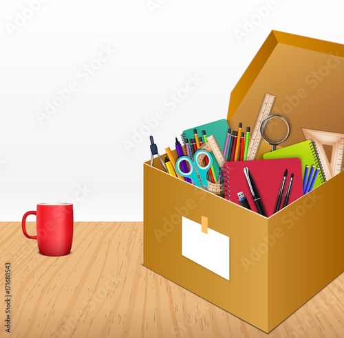 Office accessories in a cardboard box on wooden background