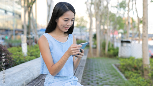 Woman using mobile phone and sitting in the park