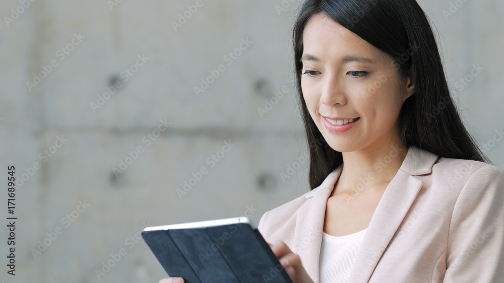 Business woman reading on digital tablet over grey park Business woman reading on digital tablet over grey park