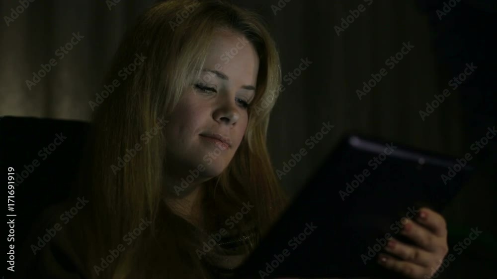 Young girl with long hair sitting with the tablet in the dark, close-up. Young girl with long hair sitting with the tablet in the dark, close-up.
