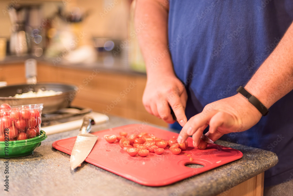 Man chopping tomatoes and preparing a healthy meal - soft focus Man chopping tomatoes and preparing a healthy meal - soft focus