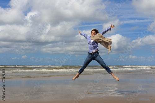 Happy young woman jumping on background of the sea.