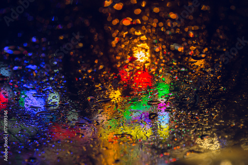 rain drop on windsheld night raining season with coloful urban city blur abstract background