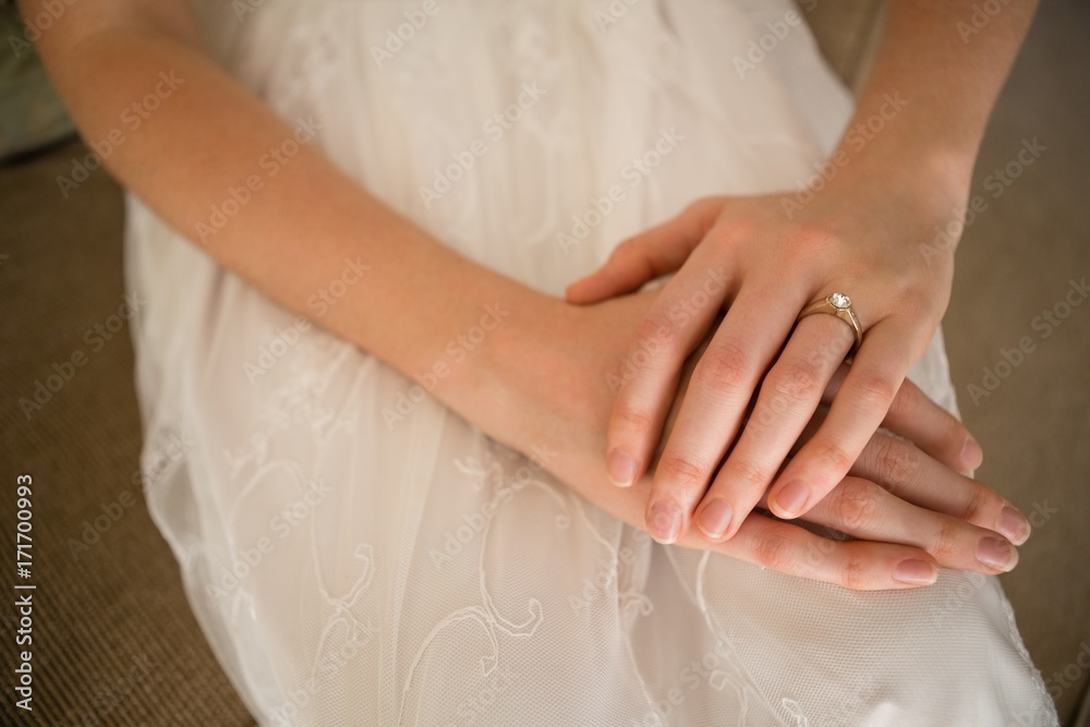 Midsection of bride wearing wedding ring while sitting on sofa Midsection of bride wearing wedding ring while sitting on sofa