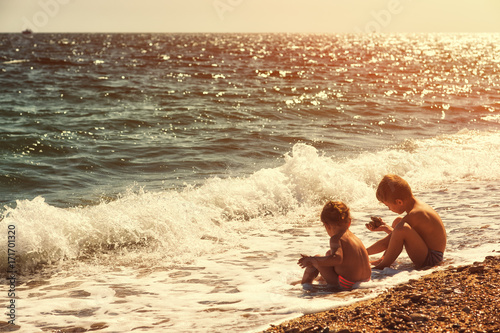 Photographie Frère et soeur jouant dans la mer en contre-jour