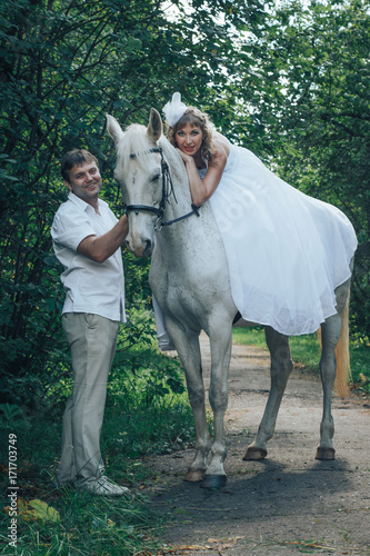 Man, bride and white horse in the park 