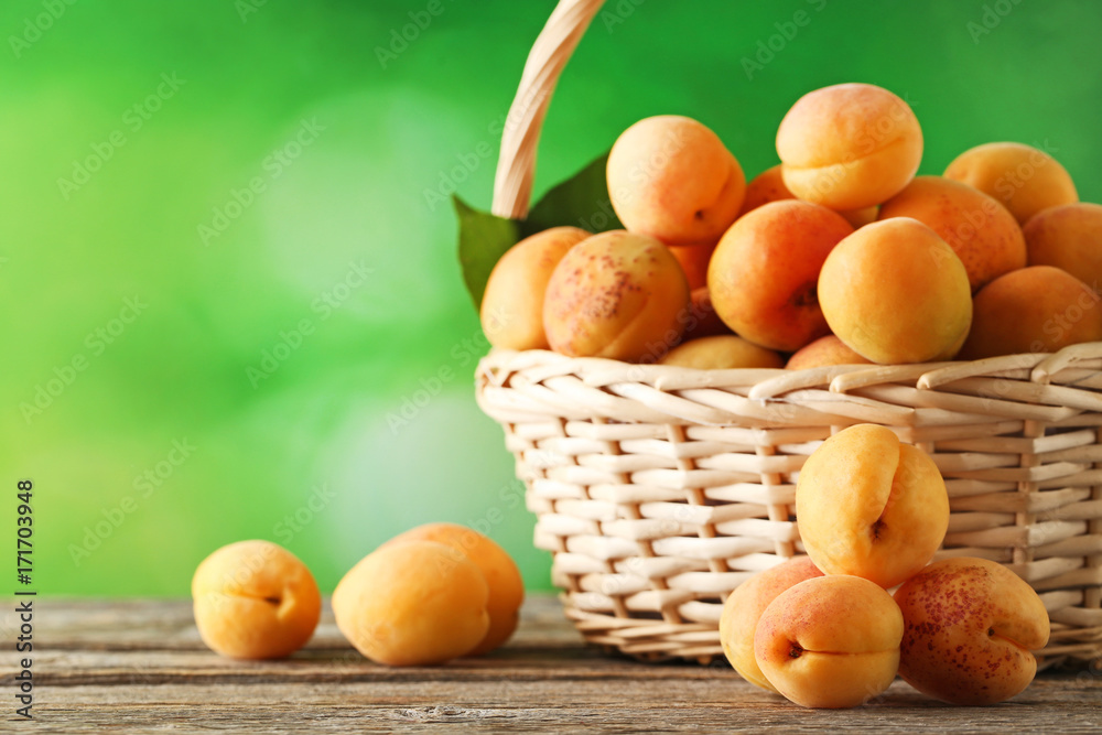 Sweet apricots in basket on grey wooden table