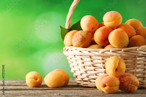 Sweet apricots in basket on grey wooden table