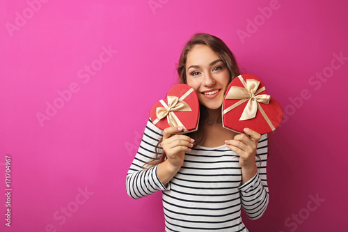 Portrait of young woman with gift box on pink background