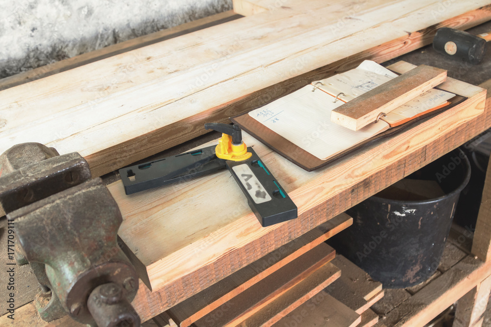 Carpenter tools, wood planks, clamp, notebook on a rusty table. Carpenter tools, wood planks, clamp, notebook on a rusty table.