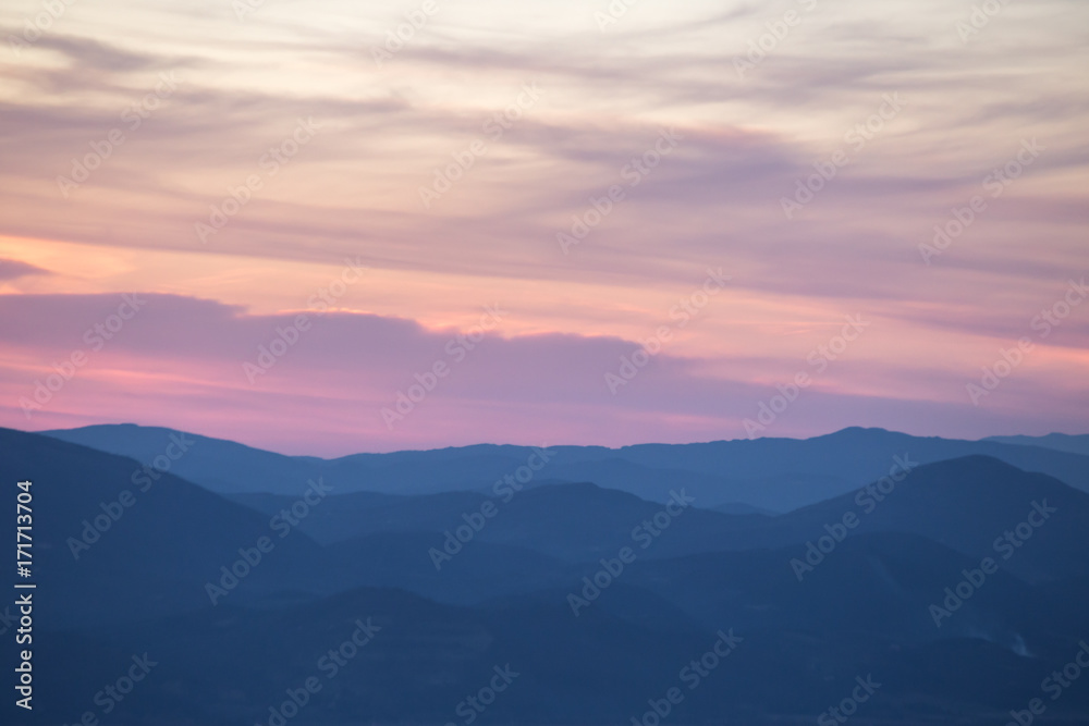 Layers of mountains and hills at sunset, with warm and soft tones