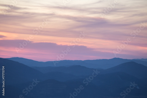 Layers of mountains and hills at sunset, with warm and soft tones