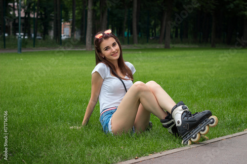 Cutie young girl with roller on her legs resting on a grass
