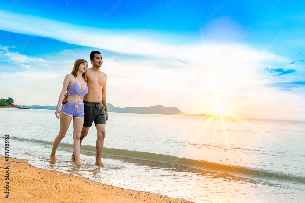 Asian couple walking on the beach when the sun is about to sunset during the honeymoon. There are  Couple walking on Valentine's Day