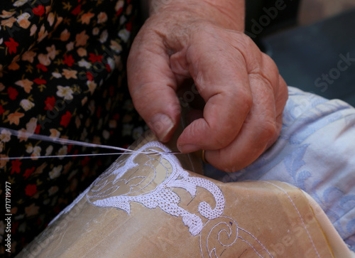 Hands of an elderly woman embroidering a lace with tombolo and c photo