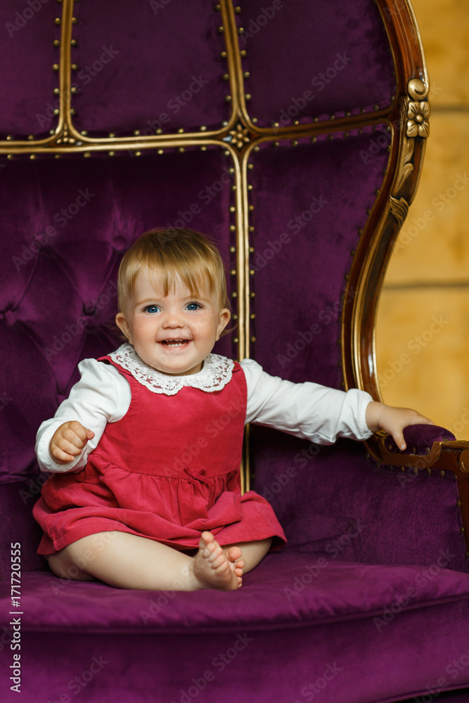 Smiling baby girl sit in purple armchair Smiling baby girl sit in purple armchair