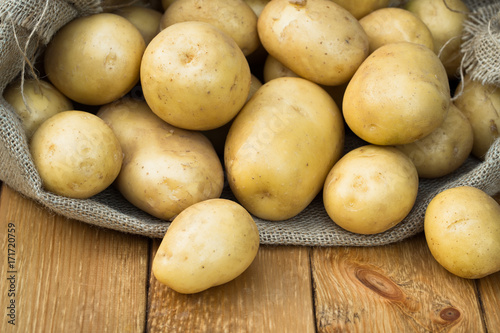 Potato. Fresh Young Yellow Potatoes In Sackcloth On Wooden Board Close Up. Healthy Food.