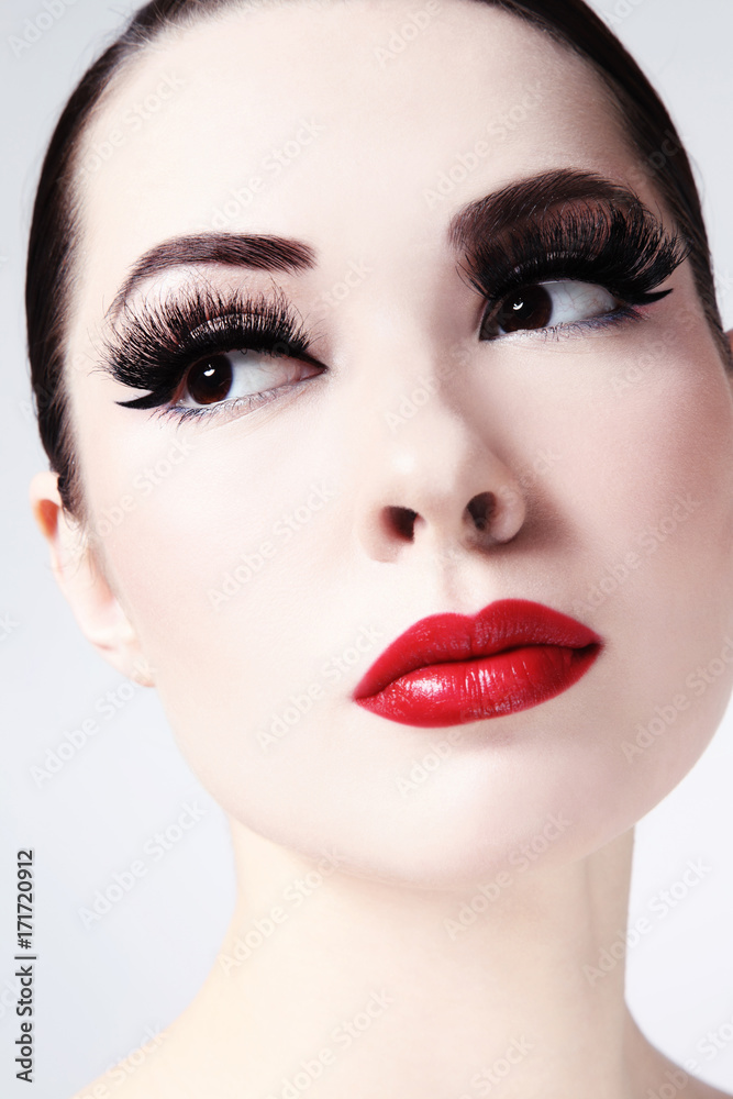 Close-up portrait of young beautiful woman with red lips and cat eye make-up