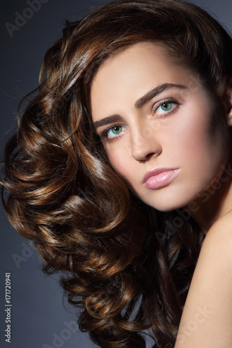 Portrait of young beautiful woman with healthy long curly hair