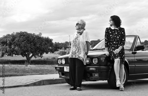 portrait of two women leaning on a car © curto