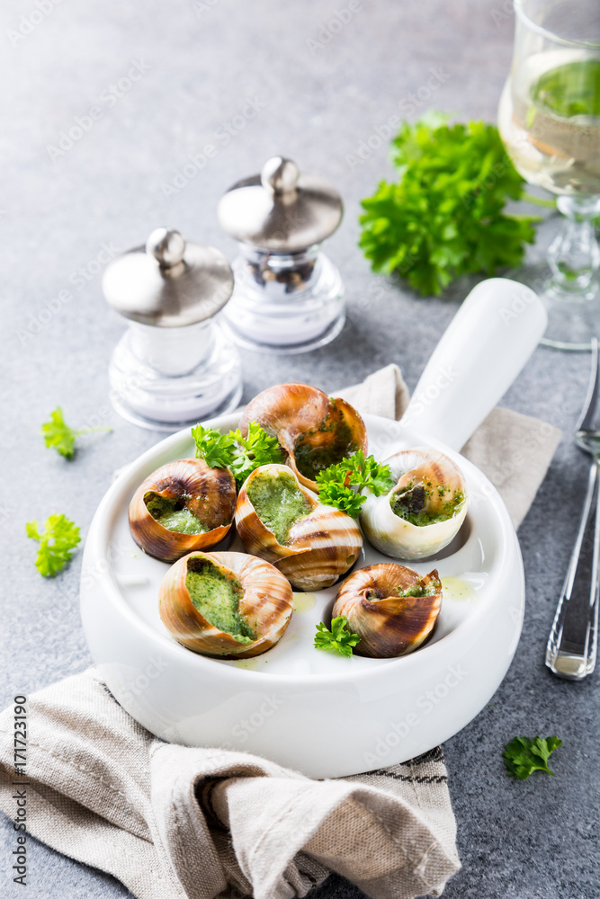 Bourgogne Escargot Snails with garlic herbs butter in white pan on light gray background. Healthy food concept.