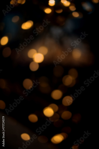 Christmas background with yellow bokeh and twinkled defocused lights. Festive blur background goldend and black lights..