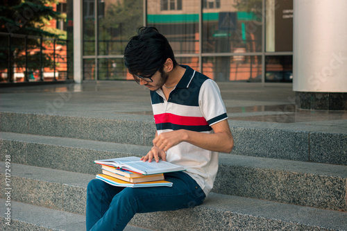 a young student in a t-shirt and glasses reading on face book