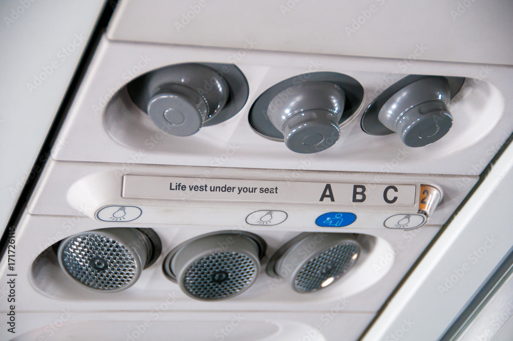 Plane inside interior. Overhead board with sign no smoking and fasten seatbelt, nobody. Blue tone Plane inside interior. Overhead board with sign no smoking and fasten seatbelt, nobody. Blue tone