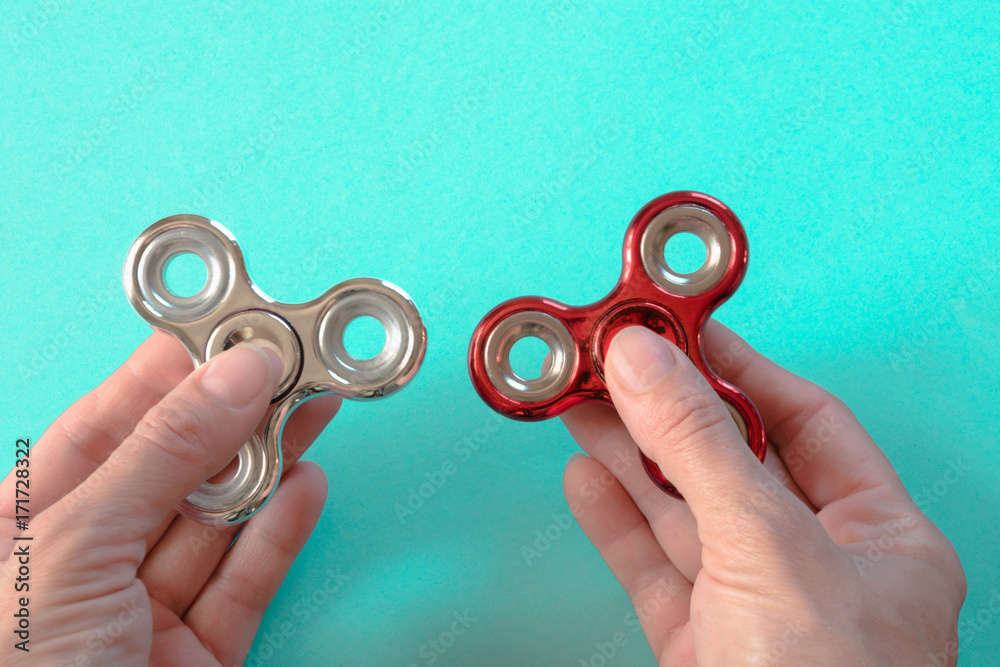 Fidget silver and red spinner stress in hand on blue.
