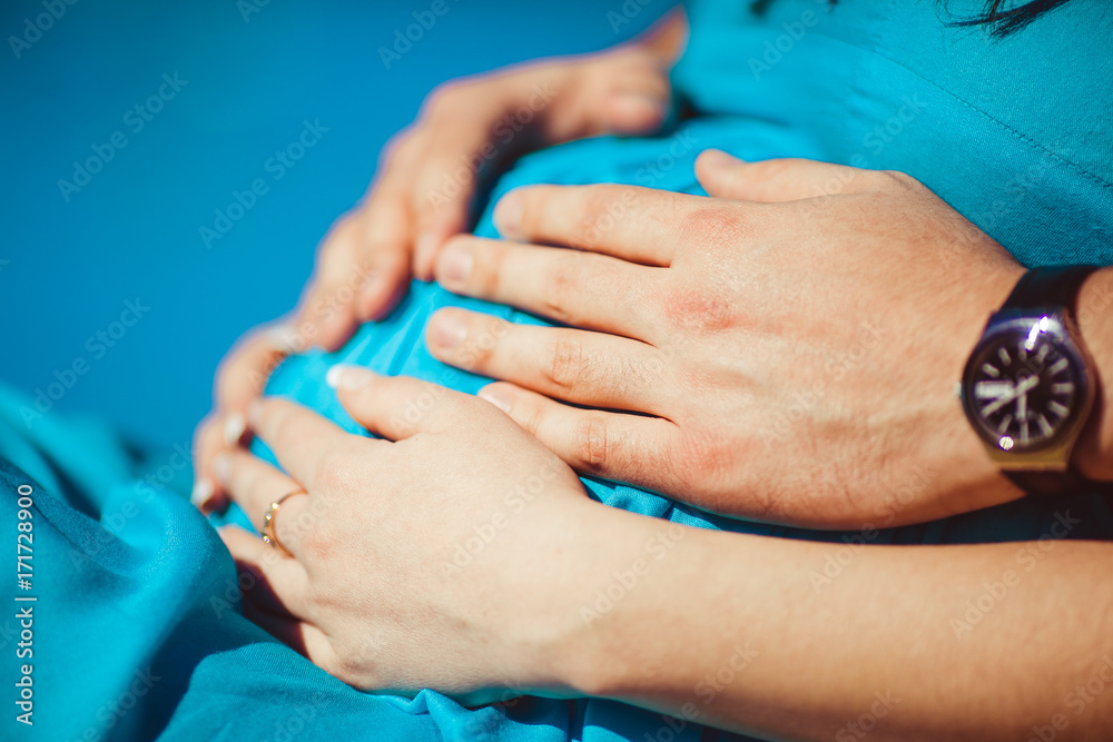 Fototapeta premium Man and woman hold their hands on a pregnant belly