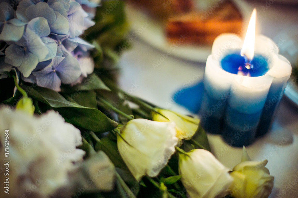 Blue candle shines before roses on dinner table Blue candle shines before roses on dinner table