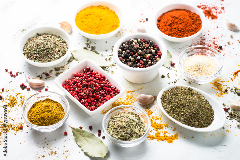 Various spices in a bowls on white table.