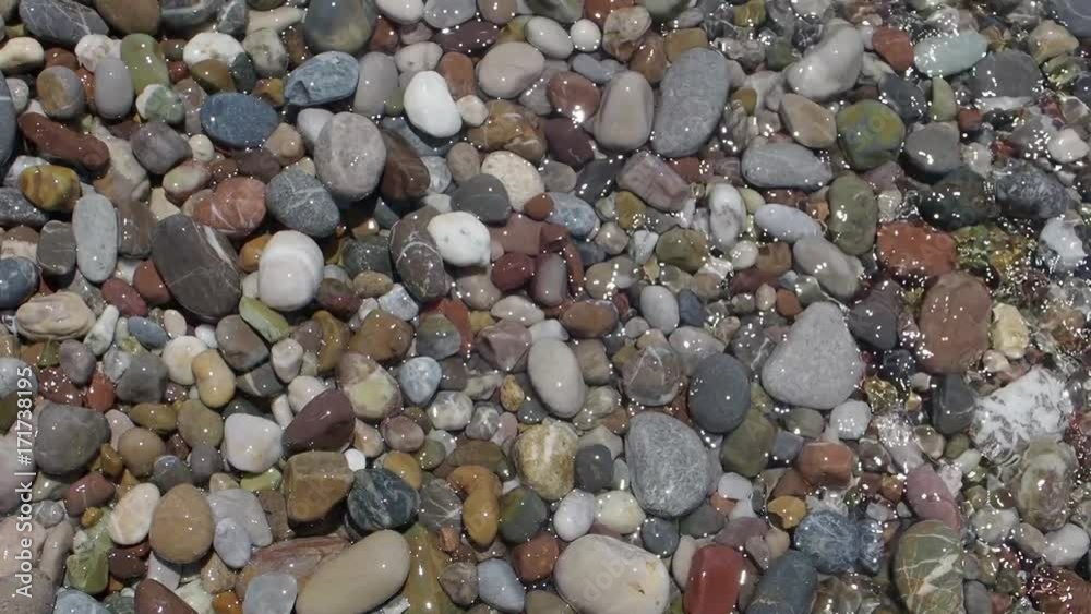 Transparent clean wave on the sea carrying small stones and pebbles along the seashore Transparent clean wave on the sea carrying small stones and pebbles along the seashore