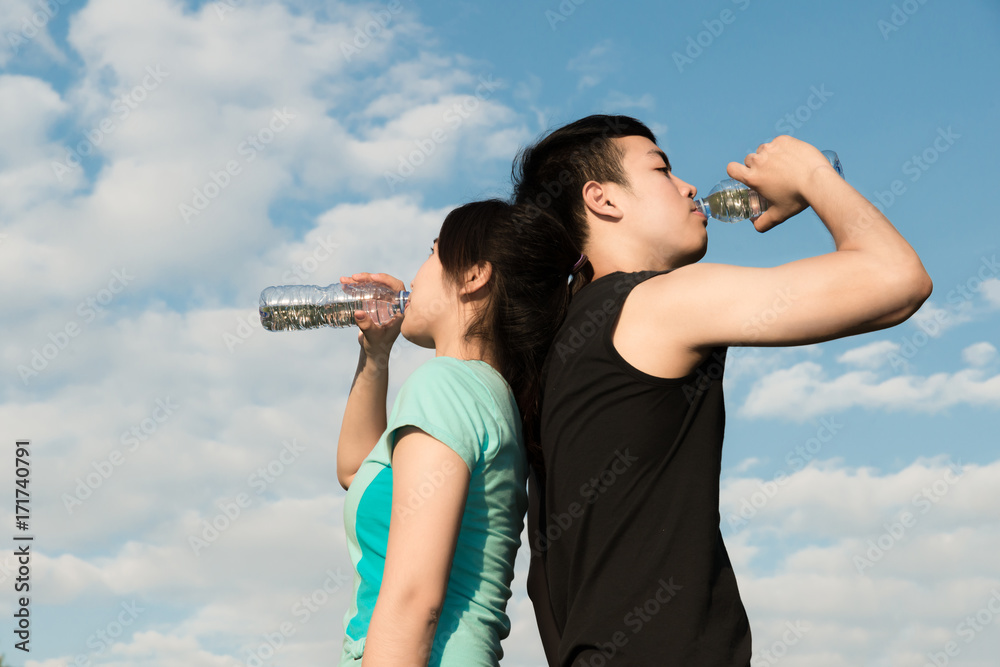 Asian couple man and woman drinking water from bottle after fitness sport exercise. Asian couple man and woman drinking water from bottle after fitness sport exercise.